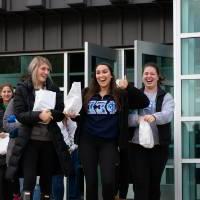 Students walking to the buses wearing Phi Sigma Sigma sweatshirts